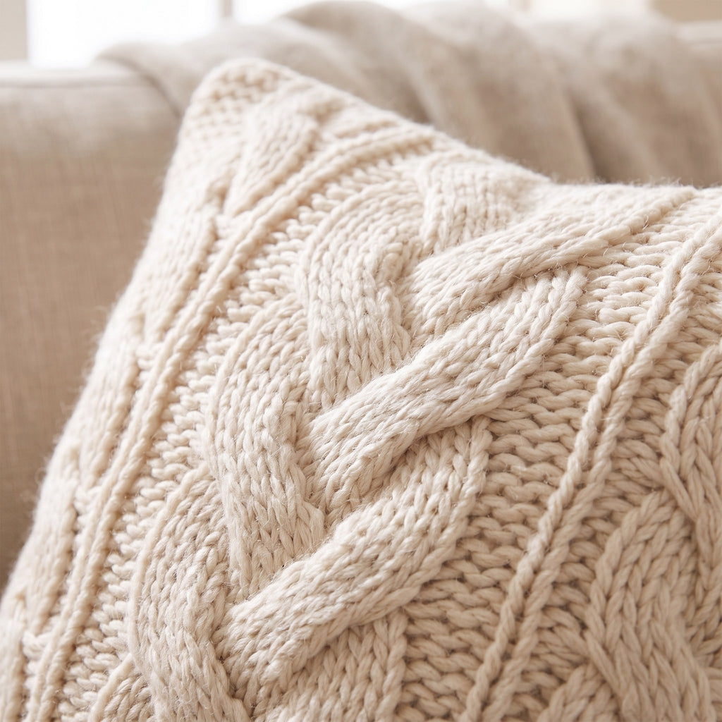 Close-up of the central cable braid and chunky stitches on the cream cushion