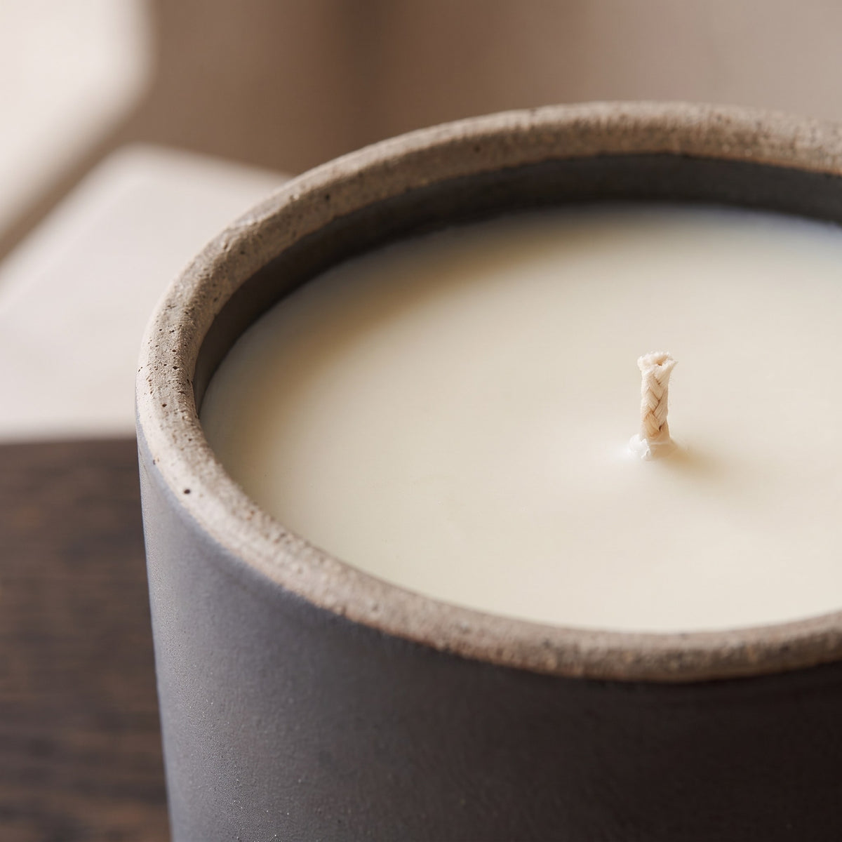 Close-up of the unglazed rim of the charcoal stoneware pot and the ivory wax with its cotton wick