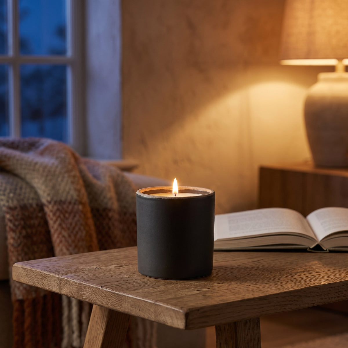 Smoked Oak & Amber stoneware candle lit on a coffee table on a winter evening
