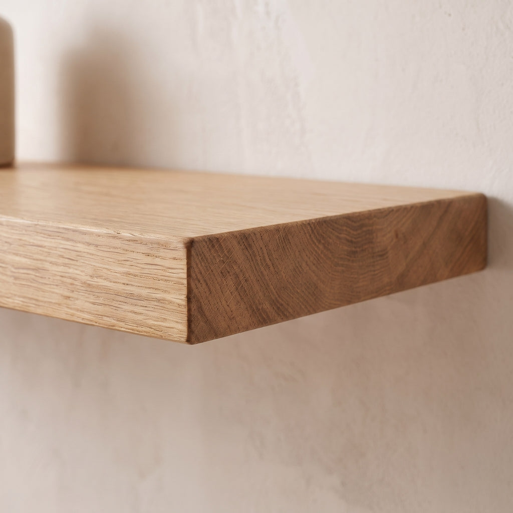Close-up of the front edge and end grain of the solid oak floating shelf against the wall