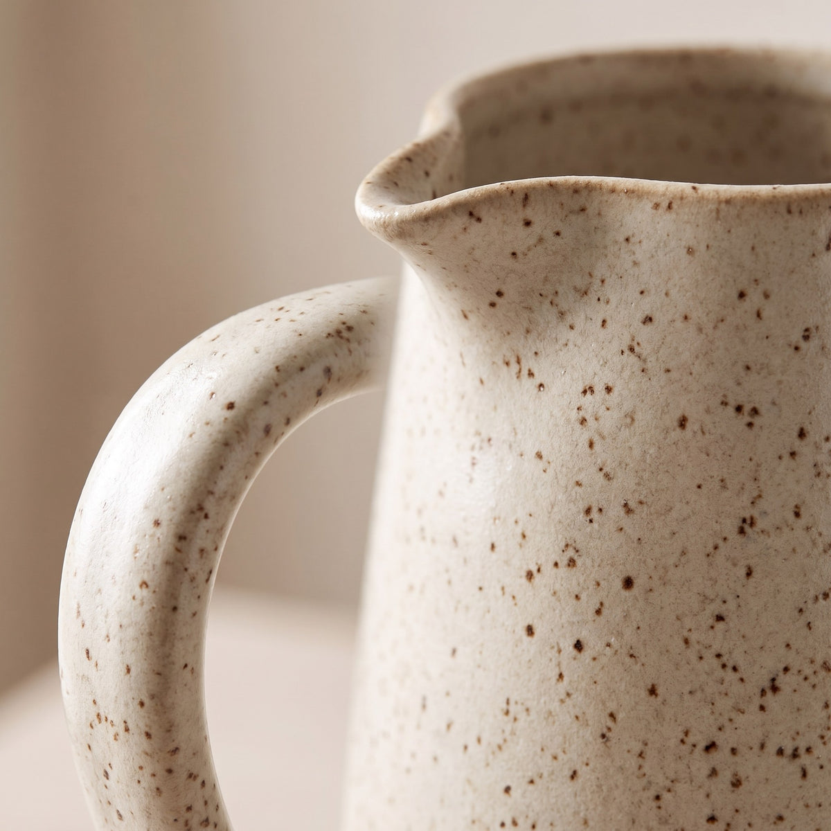 Close-up of the handle, pouring lip and brown speckled glaze of the stoneware jug vase
